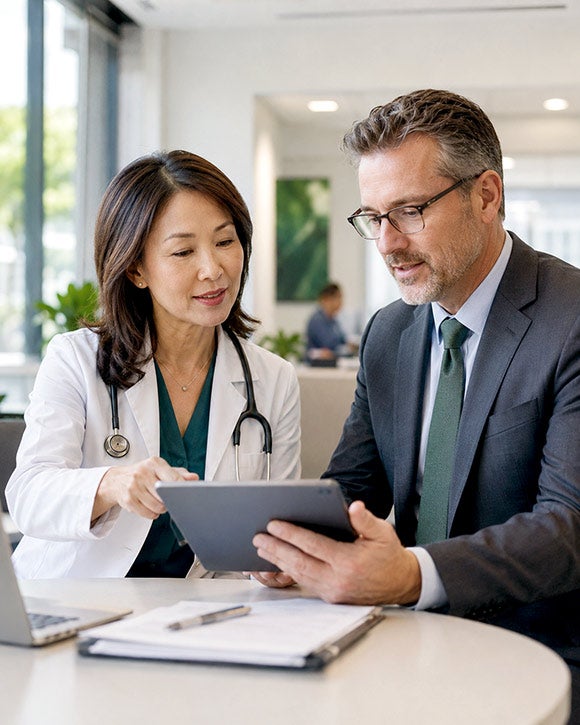 A physician executive and an administrator review information on a tablet.
