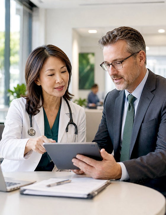 A physician executive and an administrator review information on a tablet.