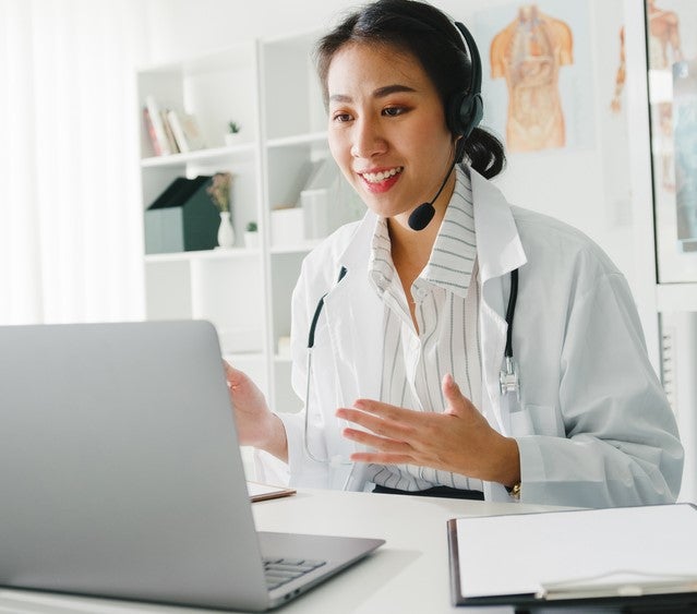 A woman wearing a headset and talking to a patient