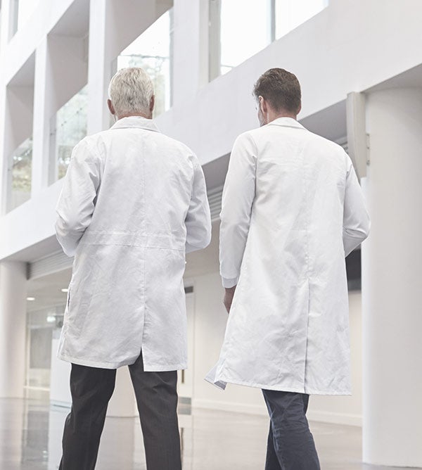 Old doctor and young doctor walking